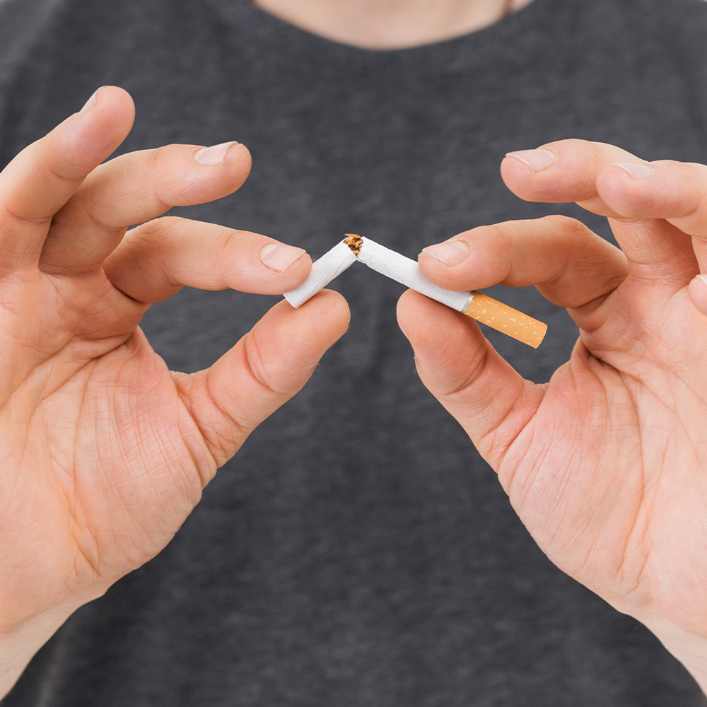 Na imagem, um homem parte um cigarro ao meio