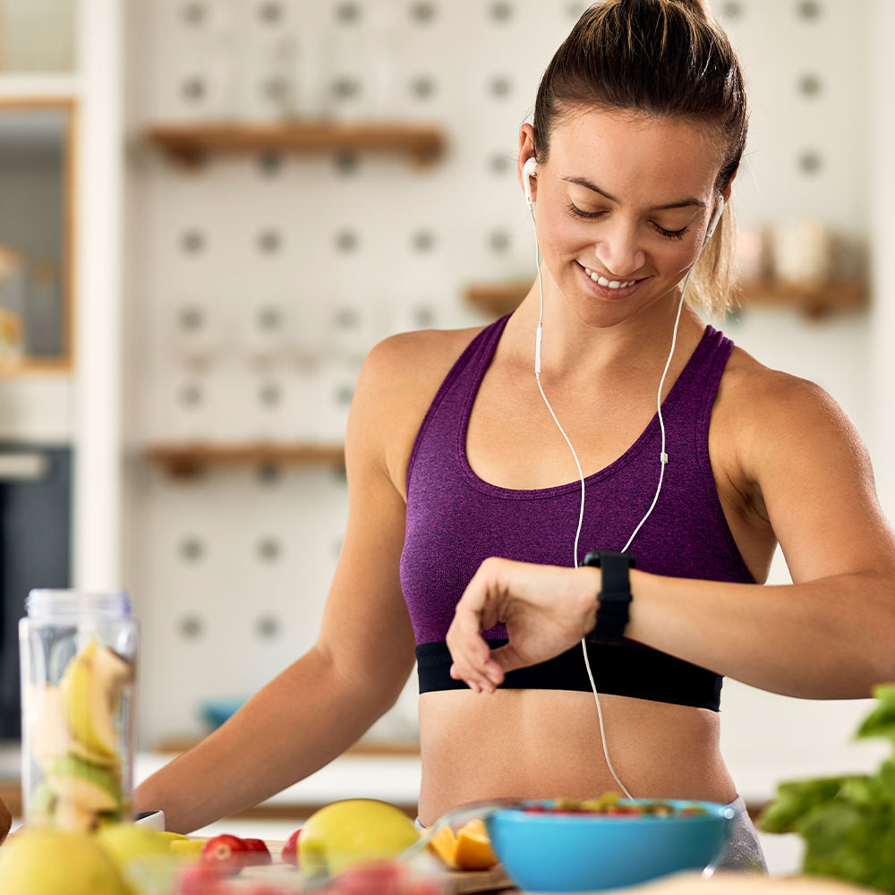 Na imagem, uma mulher fisicamente ativa preparando uma refeição saudável.
