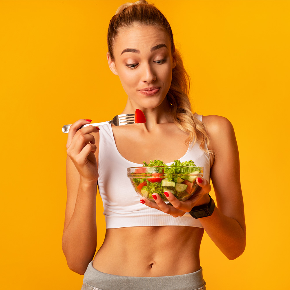 Na foto, uma mulher comendo um bowl de salada