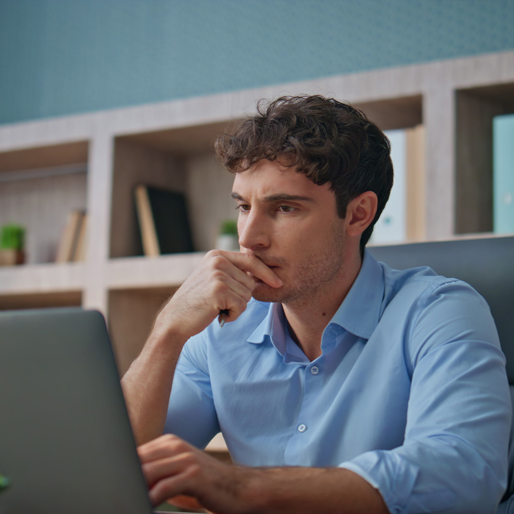 Na foto, um homem olhando para a tela do computador e pensando.